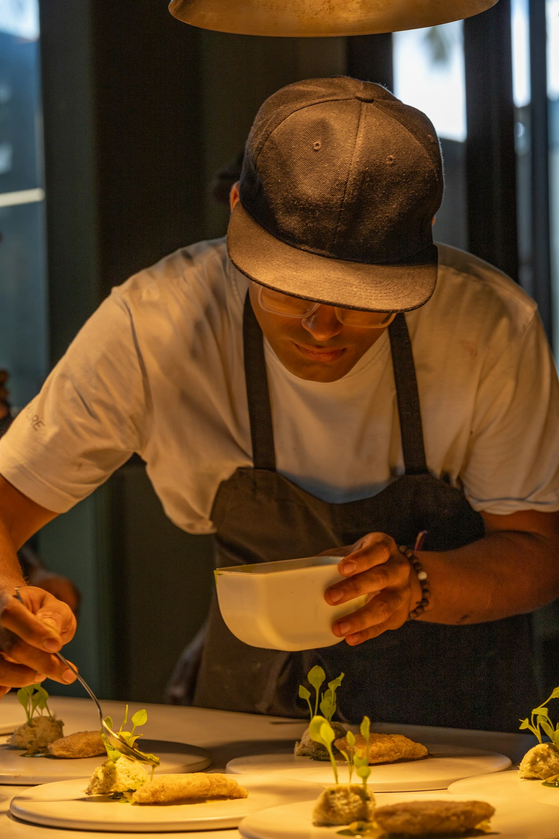Multiple bespoke dishes being plated under heat lamps in the House of Nelle kitchen